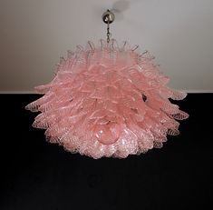 a pink chandelier hanging from the ceiling in a room with black flooring