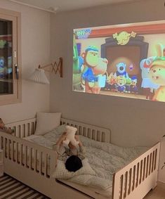 a child's bedroom with two teddy bears on the bed and a large screen in the corner