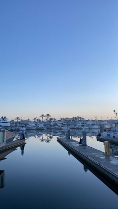 a body of water surrounded by lots of boats in the distance with blue sky above