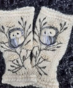 two knit mittens with an owl and tree design on the front one is white, the other is black