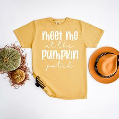 a t - shirt that says meet me at the pumpkin patch next to a hat