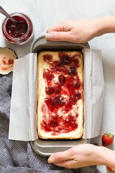 a person holding a pan with food on it and some strawberries in the background