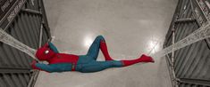 a spider man hanging upside down in the air with his hands on his hips and legs apart