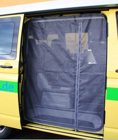 an open yellow van door with the side window partially covered by a black tarp