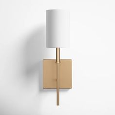 a gold wall light with a white shade on the top and bottom half of it