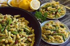 three plates of pasta with asparagus and lemons