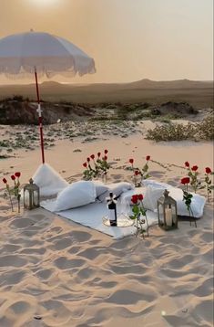 an open umbrella sitting on top of a sandy beach next to flowers and bottles filled with wine