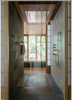 an open shower in a large bathroom with wood paneling and tile walls on the floor