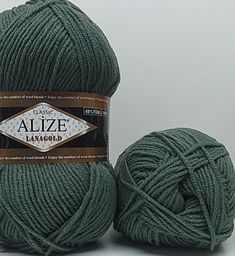 two balls of green yarn sitting next to each other on a white surface with a brown label