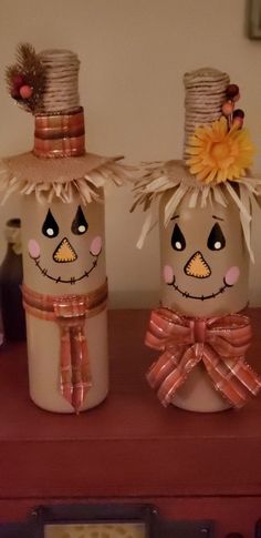 two scarecrows with hats and bows on top of a red shelf next to each other