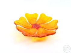 a yellow flower is sitting on a white surface with water droplets in the bottom half