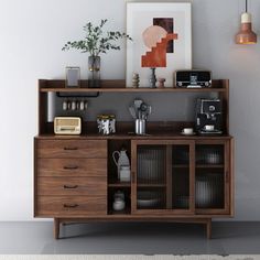 a wooden cabinet with various items on top of it and an art piece above it