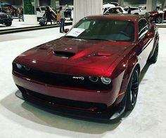 a red sports car is on display in a showroom with other cars and people