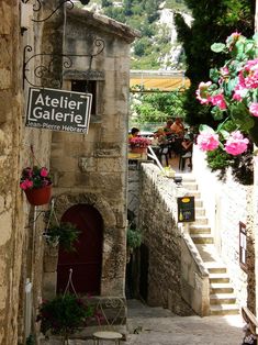 an alleyway with steps leading up to the door and flowers growing on the wall