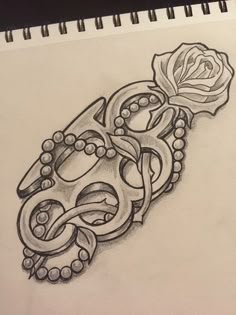 a pencil drawing of an ornate design with a rose on it's side and beads around the edges