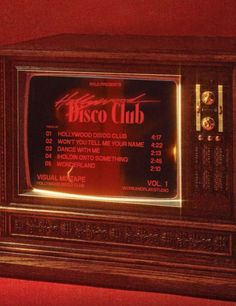 an old fashioned radio with the words disco club on it's display case in front of a red wall