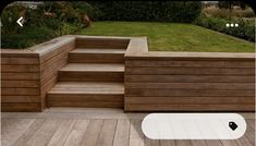 a wooden deck with steps leading up to the grass area and flowers in the background