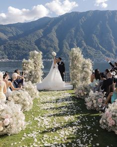 a bride and groom standing in front of an outdoor ceremony with flowers on the grass