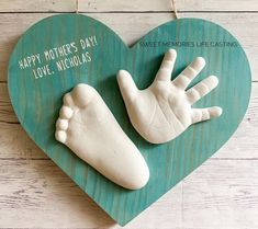 a hand and foot carved into a heart on a wooden background with the words happy mother's day love, nicholas