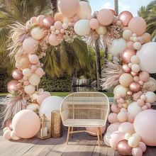 an arch made out of balloons and other decorations on a wooden deck with palm trees in the background