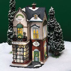 a toy house is in the snow with evergreens on it's roof and windows