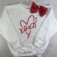 a white sweatshirt with a red bow on it