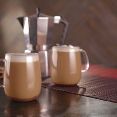 two mugs filled with liquid sitting on top of a table