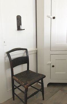 an old wooden chair sitting next to a white cabinet