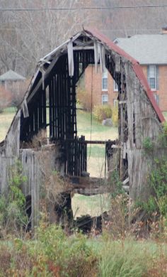 an old barn sits in the middle of a field