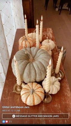 a wooden table topped with candles and pumpkins