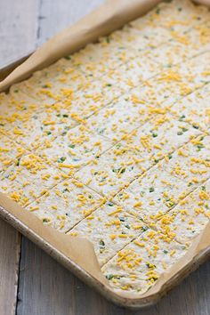 an uncooked casserole in a pan on a wooden table with yellow and green sprinkles