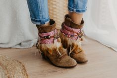 Infuse your cowgirl boots with a touch of femininity with our Pink Western Cowgirl Boot Cuffs. These stylish accessories offer a blend of rodeo-ready fashion and trendy leg warmers, elevating your cowgirl chic ensemble. Adorned with a fashionable pink hue, these cuffs are the perfect statement piece to enhance your Western-inspired footwear. Embrace the trendsetting rodeo attire with these unique and stylish boot accessories. SPECIFICATIONS * Tribal boot covers  * Features a camel-colored feathe Western Ankle Booties For Winter, Bohemian Moto Boots With Round Toe For Fall, Bohemian Winter Boots With Round Toe, Bohemian Brown Boots For Rodeo, Western Style Mid-calf Boots For Fall Festival, Bohemian Moto Boots For Festival In Fall, Bohemian Brown Winter Boots, Bohemian Rodeo Fall Boots, Bohemian Brown Boots For Western-themed Events