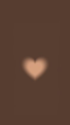 a blurry image of a heart in the middle of dark brown background with light coming from it