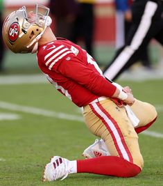 a football player sitting on the ground with his head in his hands while wearing a helmet