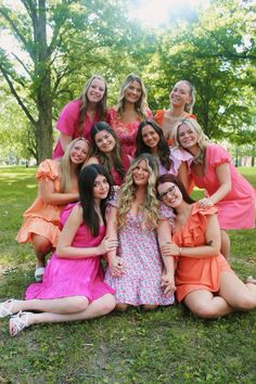 a group of young women posing for a photo together in front of trees and grass