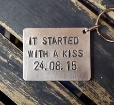 a metal keychain that says it started with a kiss 24 08 15 on the front