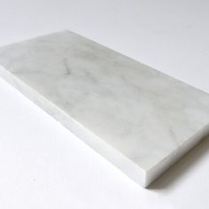 a white marble shelf sitting on top of a white countertop next to a wall