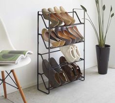 there is a rack that has many pairs of shoes on it in front of a potted plant