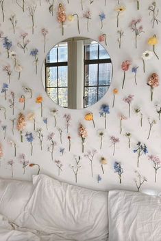 a mirror that is on the side of a wall with flowers painted on it and in front of a window