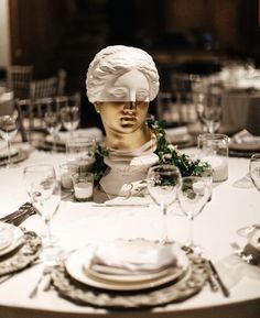 the head of a busturine is on top of a table set with silverware