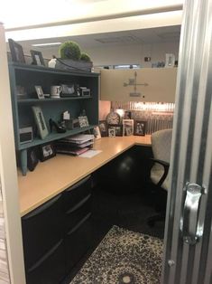 an office cubicle with desk, chair and bookshelf in the doorway to another room