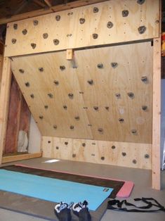 a room that has some kind of climbing wall on the wall and several pairs of shoes in front of it