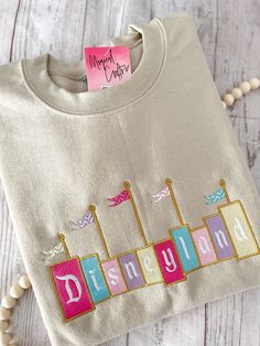 Dland Embroidered Sand Color Crewneck Sweatshirt (size up for looser fit) (colors may vary due to lighting) Embroidered Clothes Ideas, Disneyland Crewneck, Sweatshirts Ideas, Embroidery Disney, Crewneck Embroidery, Disney Trip Outfits, Embroidery Clothing, Mouse Silhouette, Cute Disney Outfits