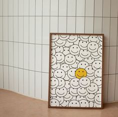 a smiley face painted on the side of a white tile wall next to a wooden frame