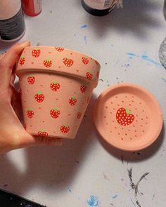 a hand holding a cup with strawberries on it and another cup next to it