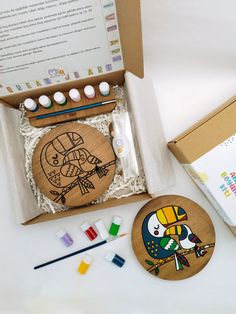 an open box with some crafting supplies in it on a white surface next to other items