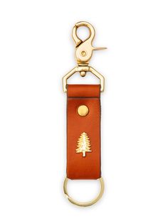 a keychain with a tree on it and a gold metal hook in the middle