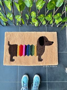 a person standing next to a rug with a dachshund on it