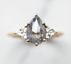 a close up of a diamond ring on a white surface with gold trimmings