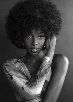 a woman with an afro is posing for a black and white photo, she has her hand on her head